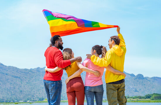 lgbt with pride flag waving in the air,talking,smiling and hugging together,happy group of multiracial lgbtq people lifestyle travel in nature