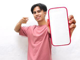 Asian young man in a pink shirt showing a smartphone screen while pointing with a happy expression...