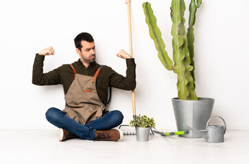 Gardener man sitting on the floor at indoors doing strong gesture