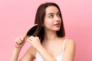 Fototapeta premium Young Ukrainian woman isolated on pink background with hair comb