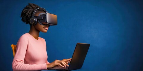 A woman uses a laptop while wearing virtual reality goggles and headphones against a plain blue background.