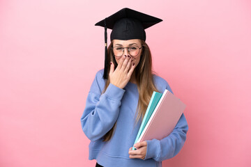 Young student woman wearing a graduate hat isolated on pink background happy and smiling covering...