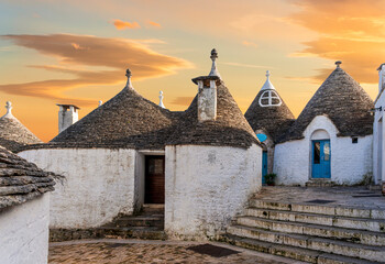 white mediterranean houses of italian trulli with white walls and beautiful roofs. Pretty vintahe buildings in style of Alberobello.