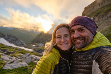 Happy couple taking selfie in mountains during sunset