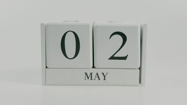A hand flips a wooden calendar from 2nd to 3rd June, representing the transition of time on a white background