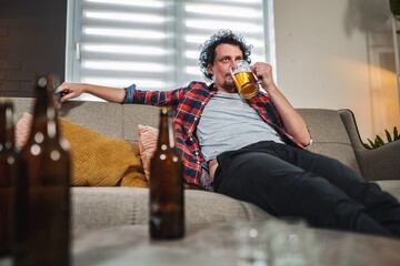 Mid adult man drinking beer at home on sofa