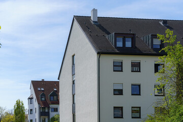 Apartment buildings in a residential neighborhood surrounded by green trees under a clear blue sky