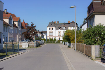 Quiet residential street in a suburban neighborhood on a sunny day with well-maintained houses and clear blue sky