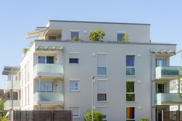Modern residential building with balconies and greenery in a vibrant neighborhood during daytime