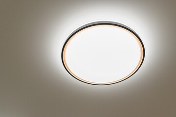 close-up of a round ceiling light. The light is white with a black frame. The ceiling is white.