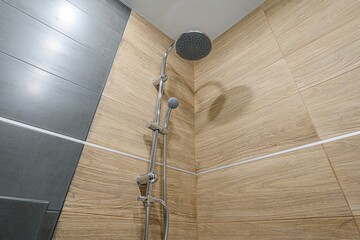 modern shower with wood-look tiles and a sleek, chrome showerhead. Grey tiles accent the space.