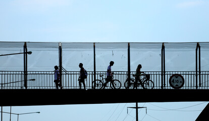 
People crossing an elevated pedestrian bridge with bicycles
