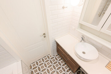 Bright bathroom features a white door, vanity with an oval sink, subway tile walls, and patterned tile floor.