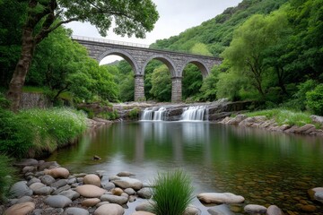 Fototapeta premium A waterfall flowing under an arched stone bridge in a lush green forest