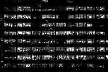 Fototapeta premium Office building at night with illuminated windows. AI image