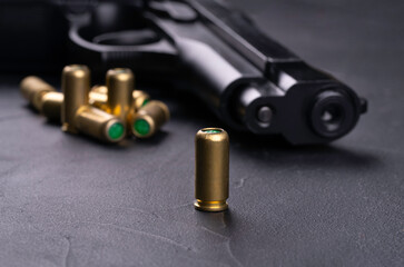 9mm pistol with blank scattered cartridges on a dark concrete background
