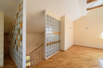modern interior featuring glass block walls, wooden floors, and a staircase. The color palette is...