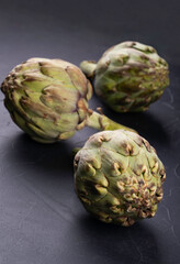 Obraz premium Scattered raw vegetables artichoke on dark bethic background