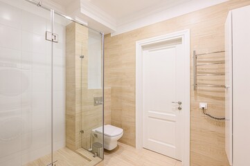well-lit bathroom featuring a glass shower enclosure, white toilet, wood-patterned tiles, and a white door. The room has a clean, modern aesthetic with chrome fixtures
