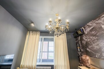 modern room features a decorative chandelier, large window with beige curtains, and a striking rock-patterned accent wall