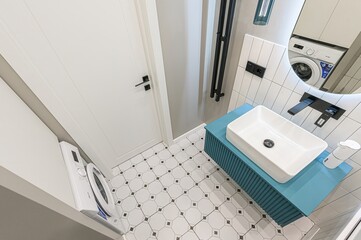 Modern bathroom with white door, patterned tiles, blue vanity, rectangular sink, black fixtures....