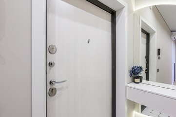 white door with silver hardware and a black frame is featured in the entryway. A mirror and console table are visible in the background