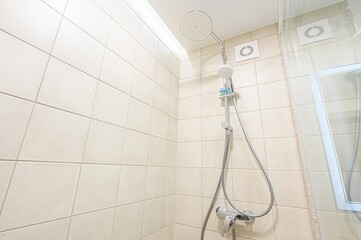 clean, tiled shower stall with a rain shower head and hand-held shower wand