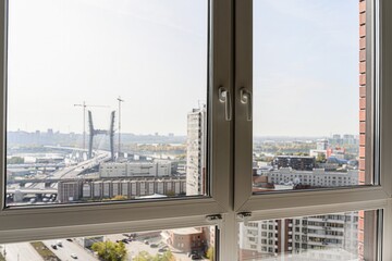 View from a window overlooking a city with a river, bridge, and buildings. The window frame is white.