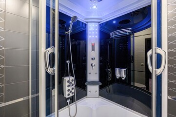 modern shower cabin with a black interior and white trim, featuring a multi-jet shower panel and...