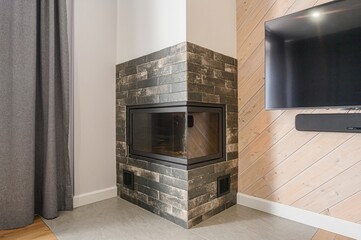 Modern living room corner features a brick fireplace, TV on a light wood panel wall, and gray...