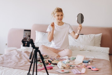 Young teenager recording her beauty blog from cozy bedroom with morning light