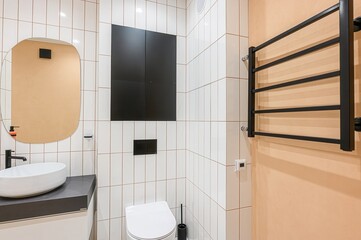modern bathroom features white vertical tiles with dark grout, contrasting with black storage and...