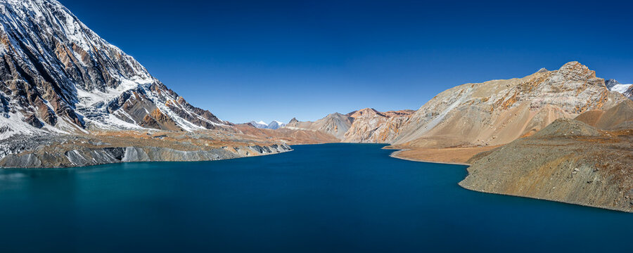 Tilicho lake with bright blue water in calm weather in autumn sunny day. Panoramic view. A sacred to Buddhists and Hindus lake in Himalaya mountain near Manang, Nepal.