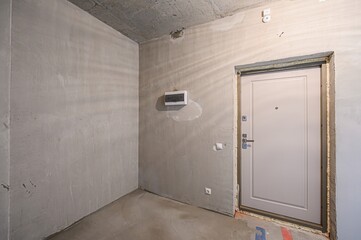 Bare, light-filled room in renovation with exposed concrete ceiling, plastered walls, and smooth...