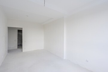 empty, all-white room with a doorway leading to another space. The walls are plain, and the floor is bare. Minimalist and clean aesthetic.