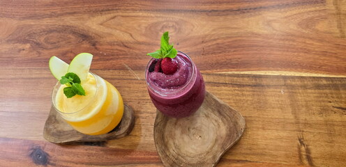 Fresh or cold-pressed juice in glass with ice on wooden board. Mixed berries, orange juice in glass garnished with mint leaves and fruits. Sliced ​​fruit garnished in glass. smoothies without sugar
