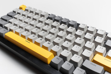Mechanical keyboard for computer on white background. Key cap of grey, black and yellow colours.