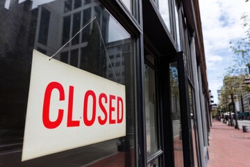 Store front displays a closed sign in a quiet urban setting on a cloudy afternoon in the city