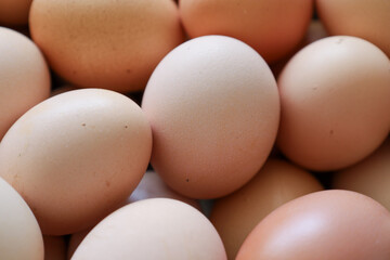 Chicken eggs of various shades of brown lie tightly against each other, occupying the entire space of the image. Their smooth shells reflect light.