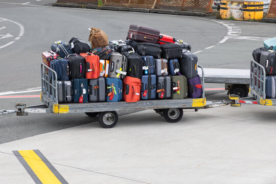 Colorful luggage stacked on airport baggage cart