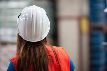 concentrated female asian warehouse worker preparing to work. motivated girl walking ready for work. female employee concentrated preparing for working with packaging wearing safety vest and helmet