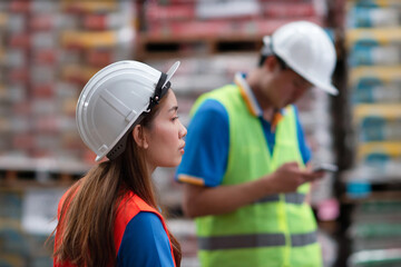 concentrated female asian warehouse worker preparing to work. motivated girl walking ready for work. female employee concentrated preparing for working with packaging wearing safety vest and helmet