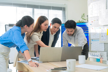 Group of business people reviewing financial charts and laptop insights while standing in office...