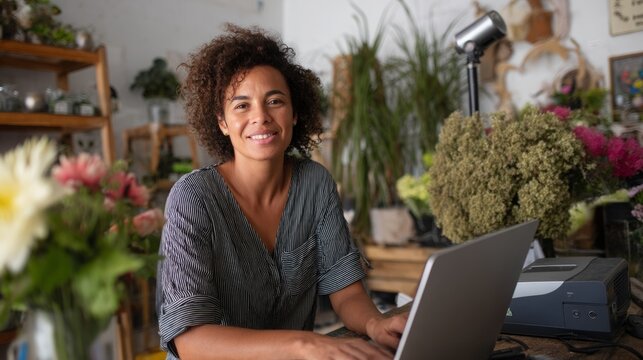Smiling African American woman working at her flower shop on a laptop