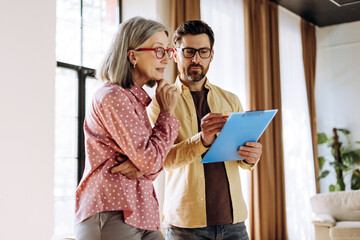 Financial advisor showing contract details to thoughtful senior woman