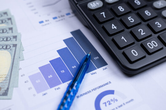 A calculator, pen, cash, and financial charts represent financial analysis and business performance review. - Powered by Adobe