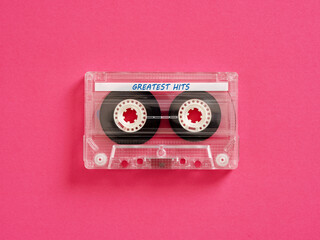 Transparent audio cassette tape lying on pink background