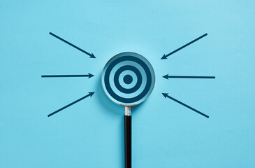 Magnifying glass focusing on target surrounded by arrows on blue background © Cagkan