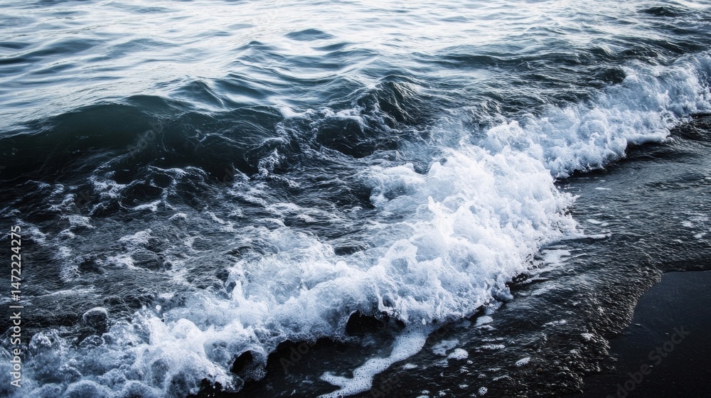 Poster ocean wave breaking on a dark sandy beach, creating a beautiful contrast of white foam and deep blue