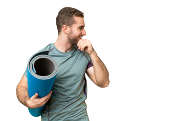 Young sport man going to yoga classes while holding a mat over isolated chroma key background thinking an idea and looking side